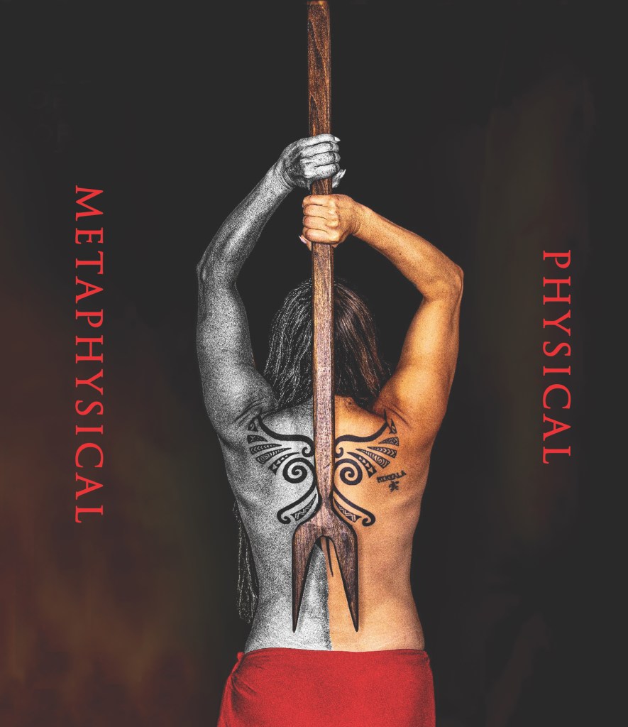 A conceptual and artistic photograph of a person from the back, holding a long, wooden, two-pronged fork-like staff vertically in the center. The person's body is divided vertically into two distinct halves: the left side is in grayscale, depicting an arm and back with a black tribal tattoo, while the right side is in warm, golden tones, showing an arm and back with another tribal tattoo. The person's hair is long and flows down their back. They are wearing a red cloth draped around their lower body. The words "METAPHYSICAL" are written vertically in red on the left side of the image, and "PHYSICAL" are written vertically in red on the right side. The background is a dark, gradient mix of red and black.