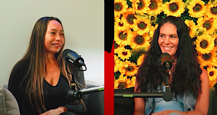 Dr. Michelle Manu (left) and another woman engage in a podcast conversation, each seated in front of a microphone. Dr. Manu wears a black top and smiles slightly, while the host on the right, seated in front of a vibrant sunflower-patterned backdrop, smiles warmly. The setup suggests a casual, yet professional podcast recording session.